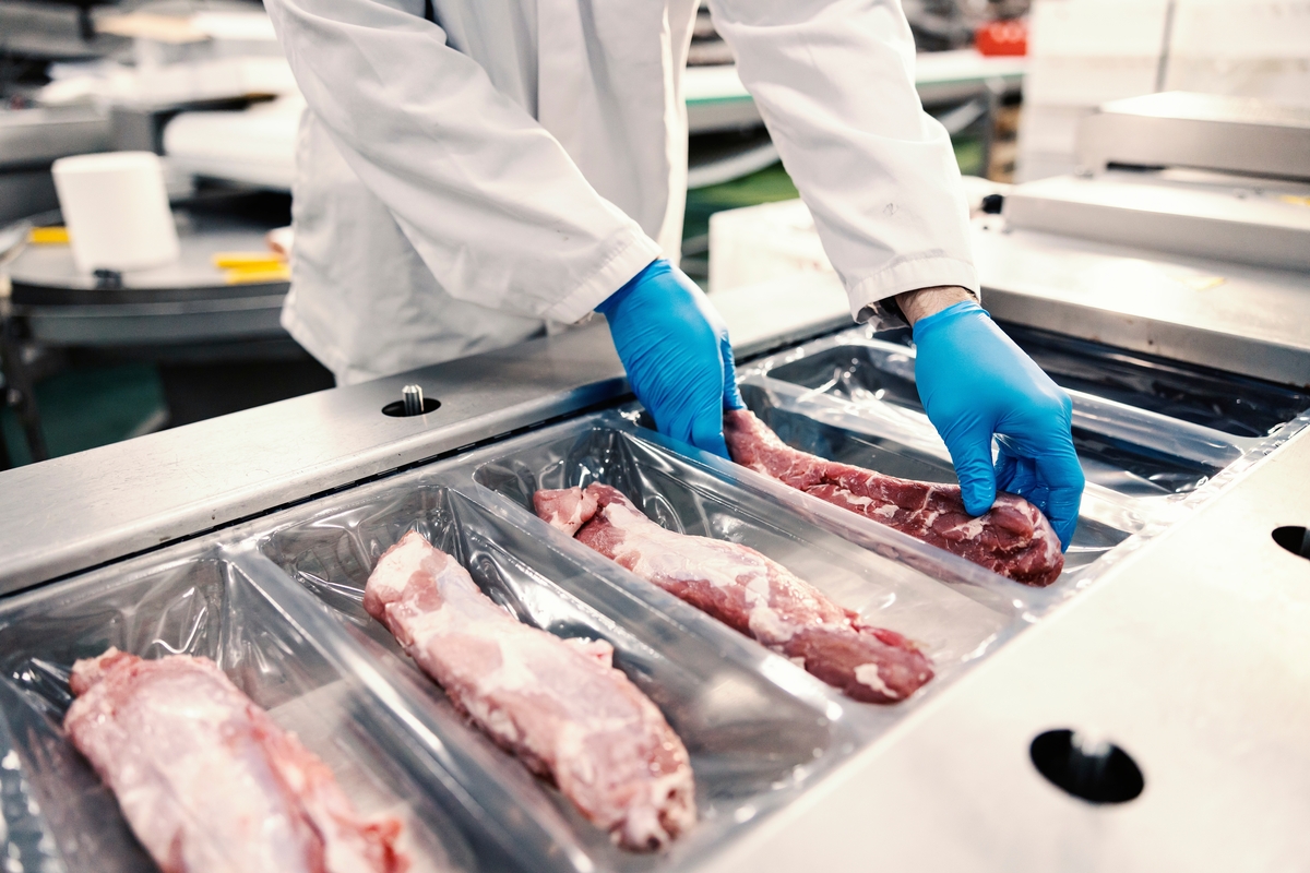 Close,Up,Of,A,Food,Factory,Worker,Packing,Meat,Into